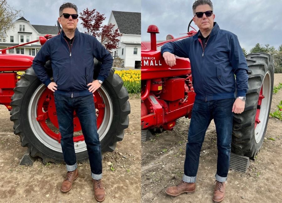 Timothy standing in front of a red tractor wearing Baracuta's G9 Harrington Jacket with selvedge denim and boots