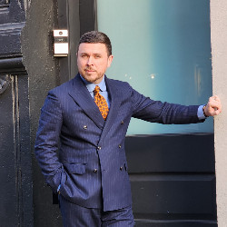 J FitzPatrick, men's shoe and style expert, posing in a nav blue suit