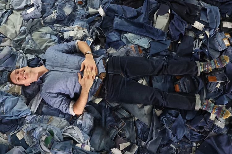 Nick on a pile of denim jeans