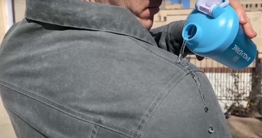 pouring water on a wax jacket to show it is waterproof