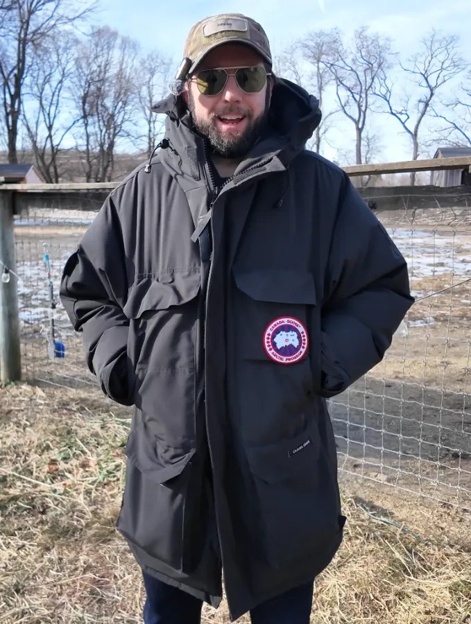 Canada goose jacket in field both hands in pockets